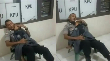 polisi jaga kotak suara sambil momong anak