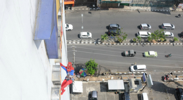 spiderman sedang bergelayutan diatas gedung