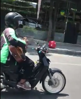 driver ojek online main gitar sambil naik motor