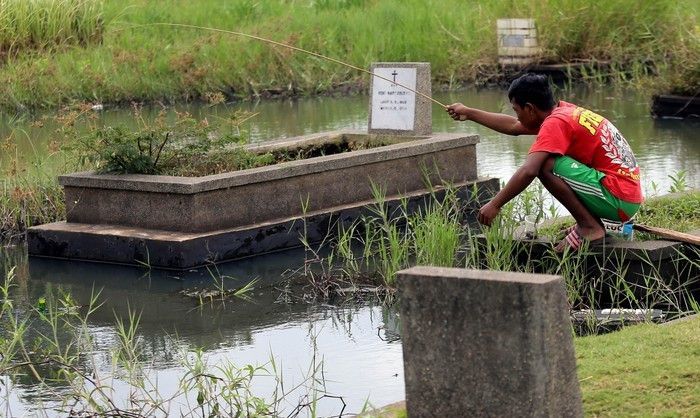 Bocah mancing di kuburan