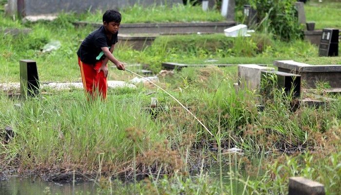 Bocah mancing di kuburan